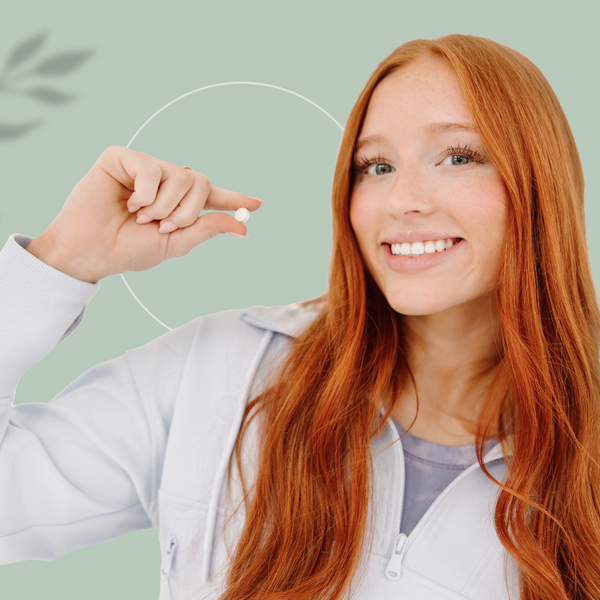 Smiling woman holding an Ora-Protek oral probiotic lozenge — easy daily oral care routine